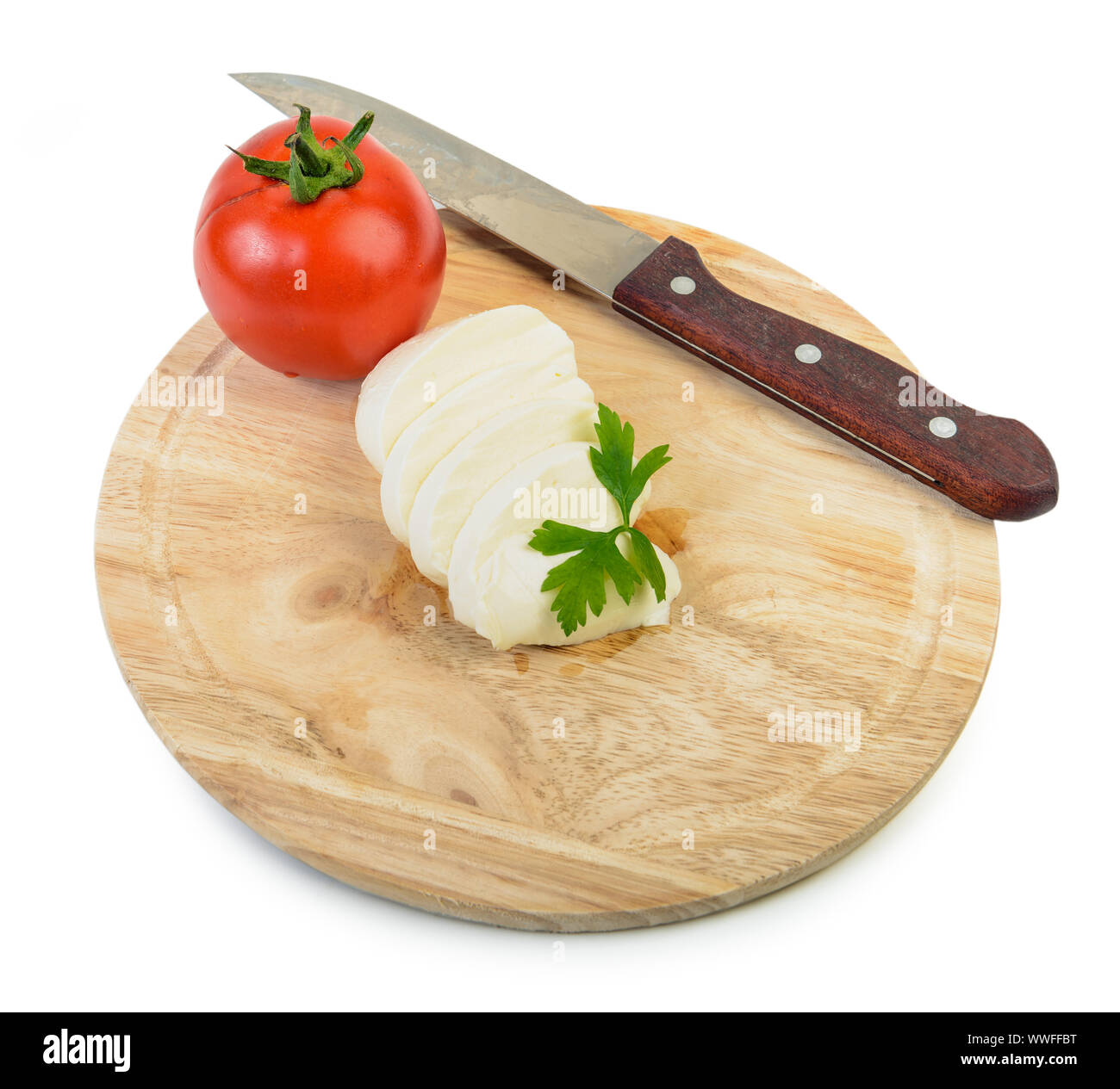 Stück Mozzarella Büffel auf Holzbrett mit Messer und Cherry Tomaten auf weißem Hintergrund. Mit Petersilie Kraut eingerichtet. Freistellungspfad Stockfoto