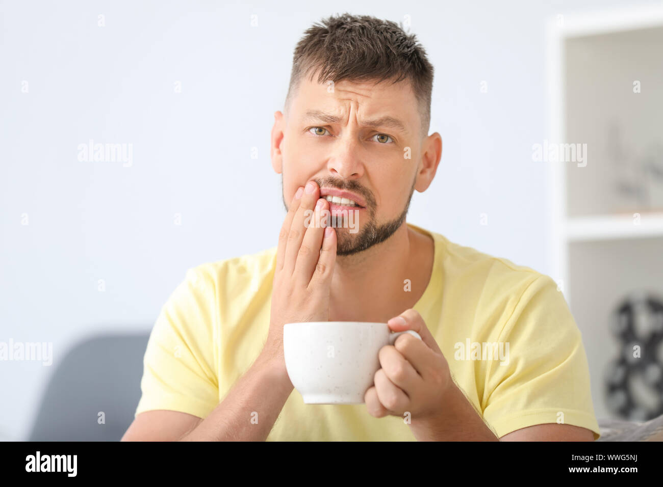 Mann mit empfindlichen Zähnen und heißem Kaffee zu Hause Stockfoto