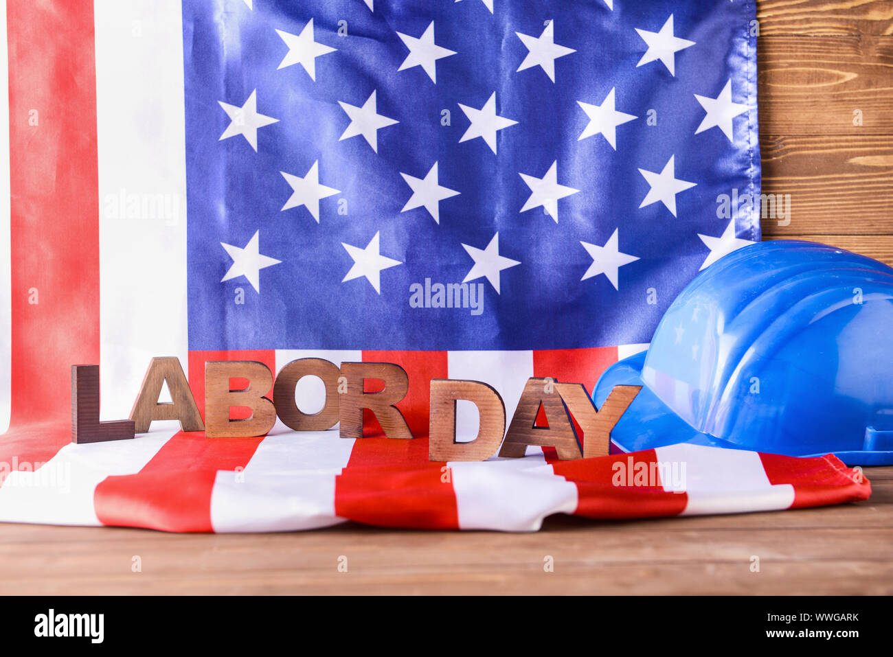 USA-Flagge, hardhat und Text TAG DER ARBEIT auf hölzernen Tisch Stockfoto