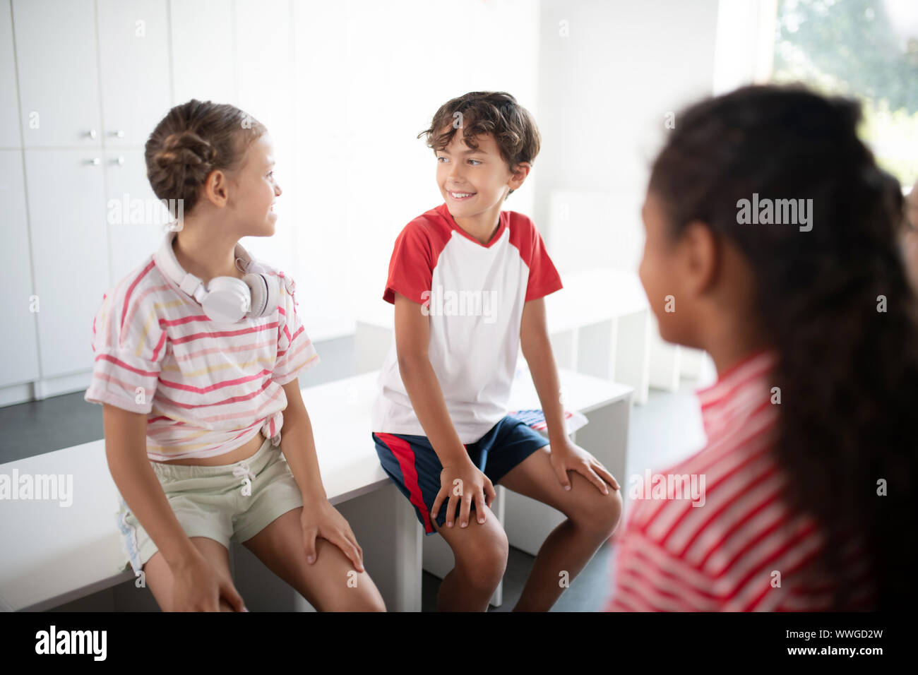 Mädchen mit Ohrhörer am Hals sprechen mit ihrer Klassenkameradin Stockfoto