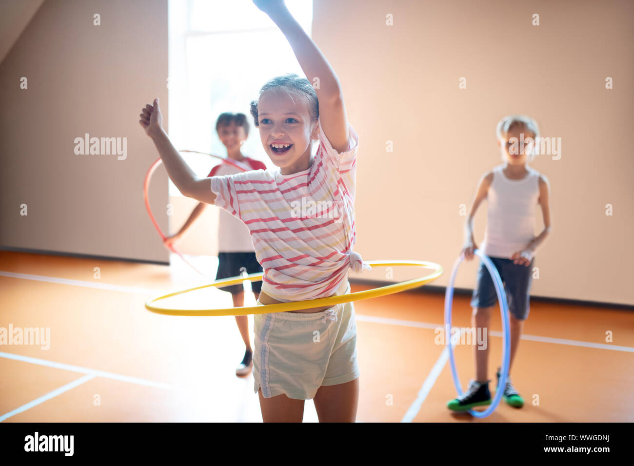 Mädchen mit gestreiften T-Shirt Lächeln beim Rollen hula - Hoop Stockfoto