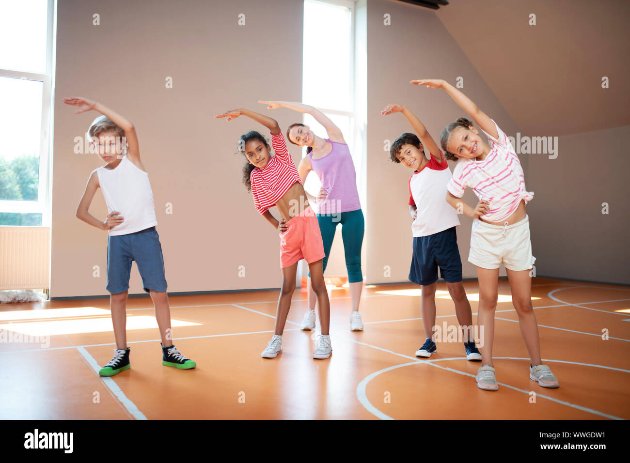 Schüler und Sportlehrer arbeiten an Flexibilität vor Beginn der PE-Lektion Stockfoto