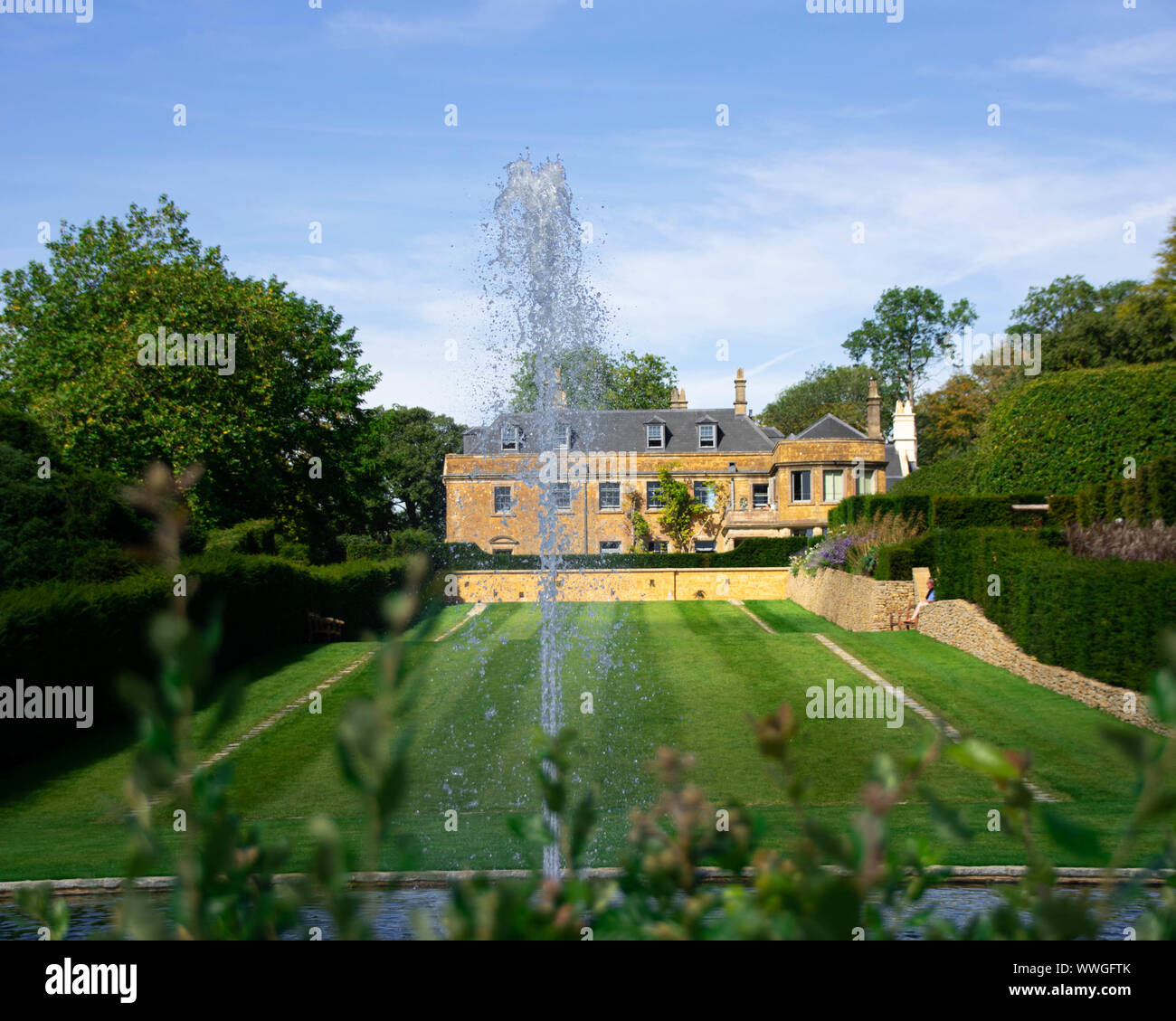 Ein wunderschönes Herrenhaus im Herzen von Somerset durch einen Brunnen im Vordergrund gesetzt Stockfoto