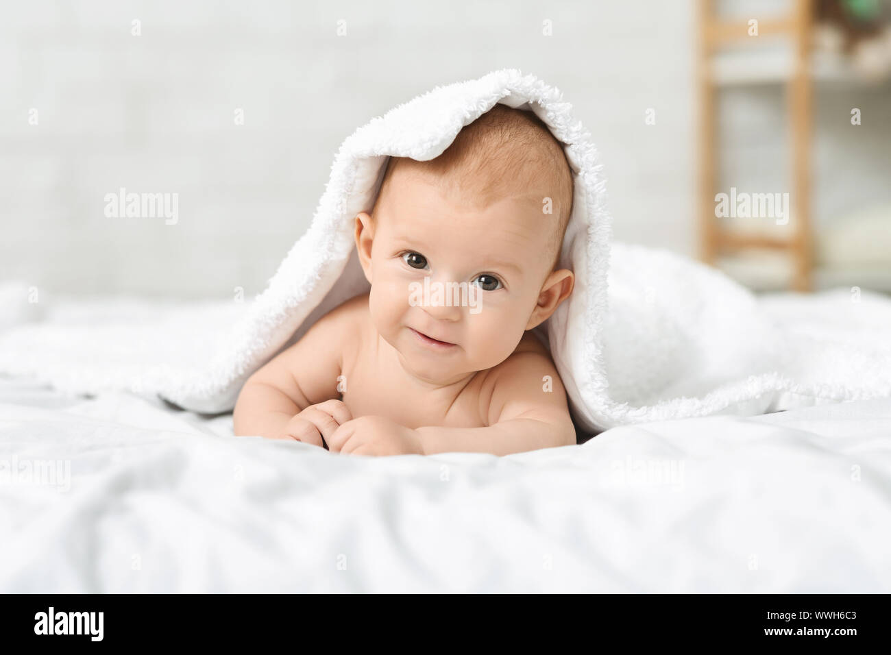 Adorable Baby boy Kriechen auf Bett und versteckt unter Vertrag Stockfoto