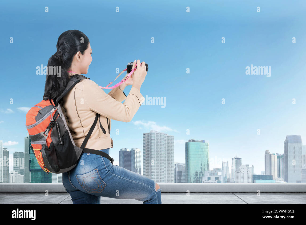 Ansicht der Rückseite des asiatischen Frau mit einem Rucksack mit einer Kamera auf dem Dach des Gebäudes zu nehmen Stockfoto