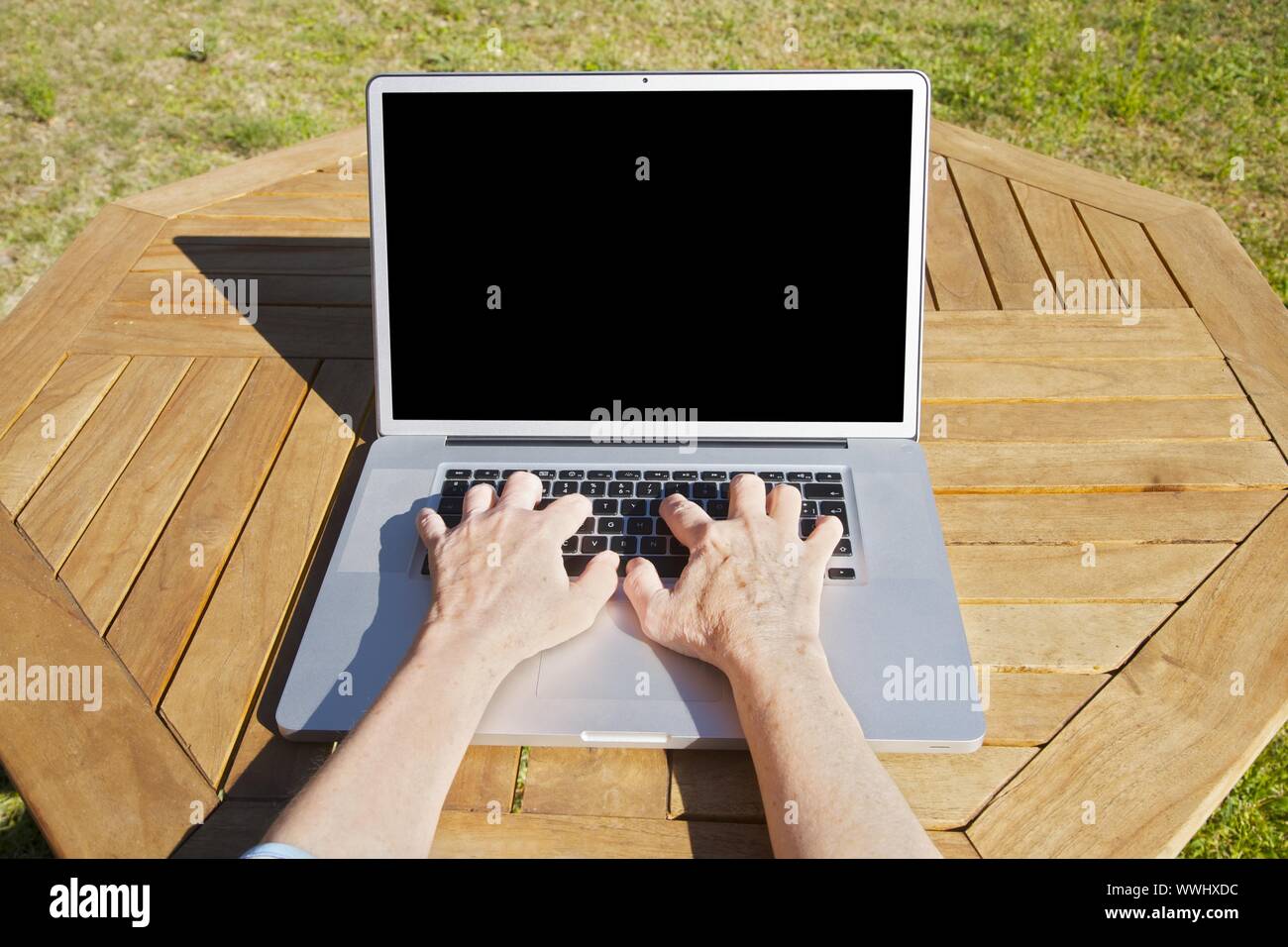 Hände der alten Frau, die auf tragbaren Computer tippen Stockfoto