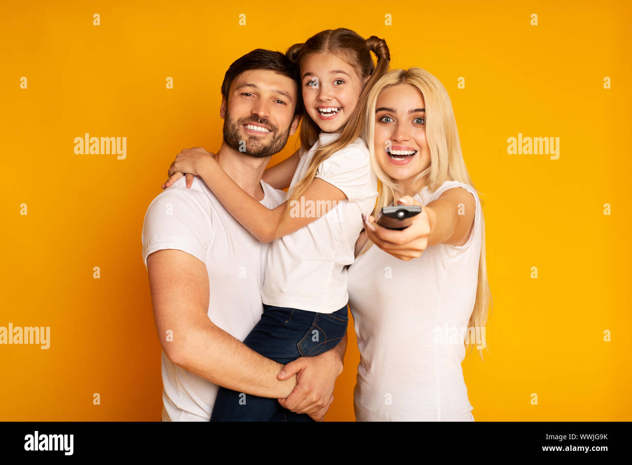 Glückliche Eltern und Tochter Schaltkanäle Fernsehen, Studio Shot Stockfoto