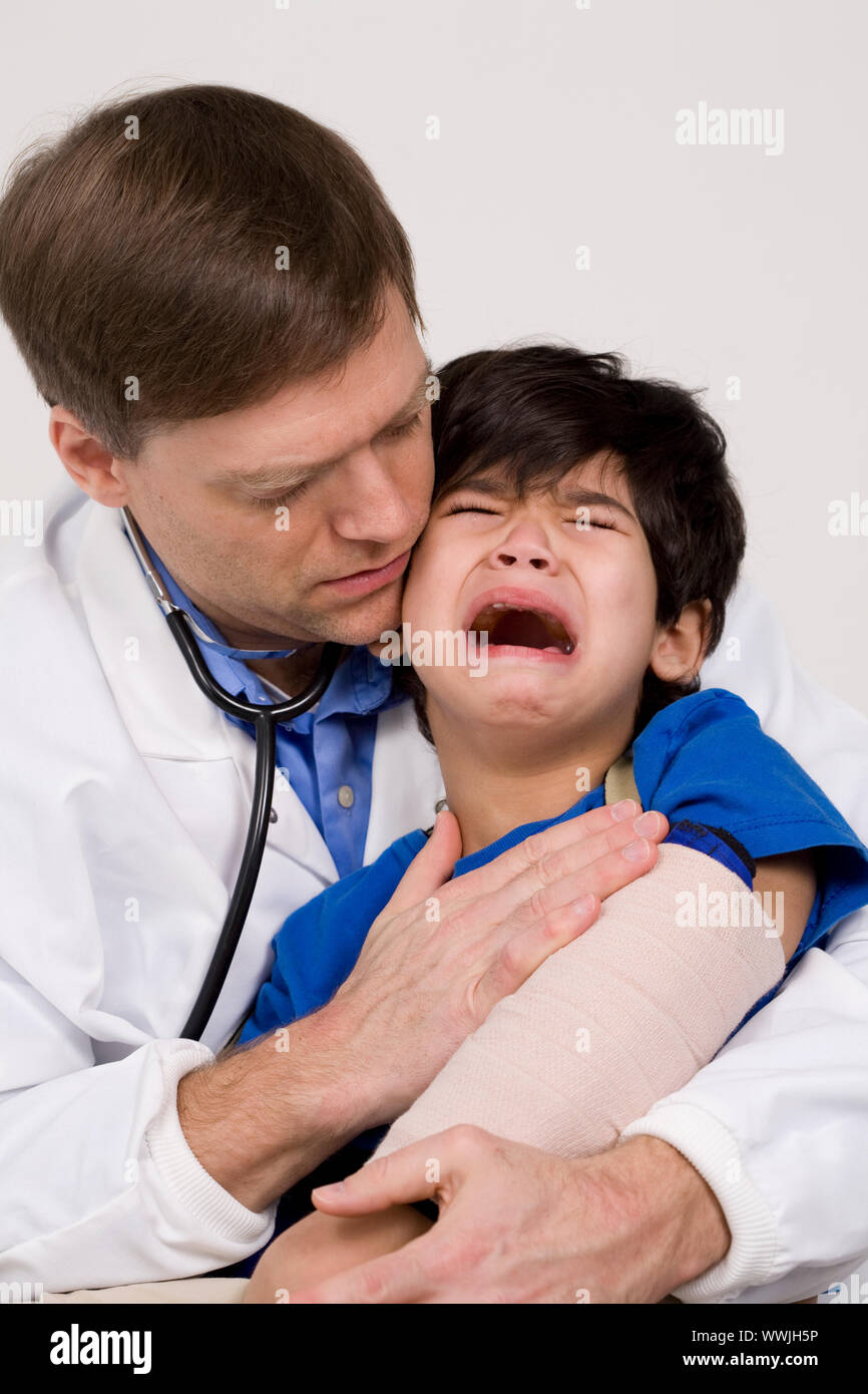 Männlicher Arzt Anfang der vierziger Jahre beruhigende fünf Jahre alte behinderte Patienten während der Office besuchen Sie erschrocken Stockfoto