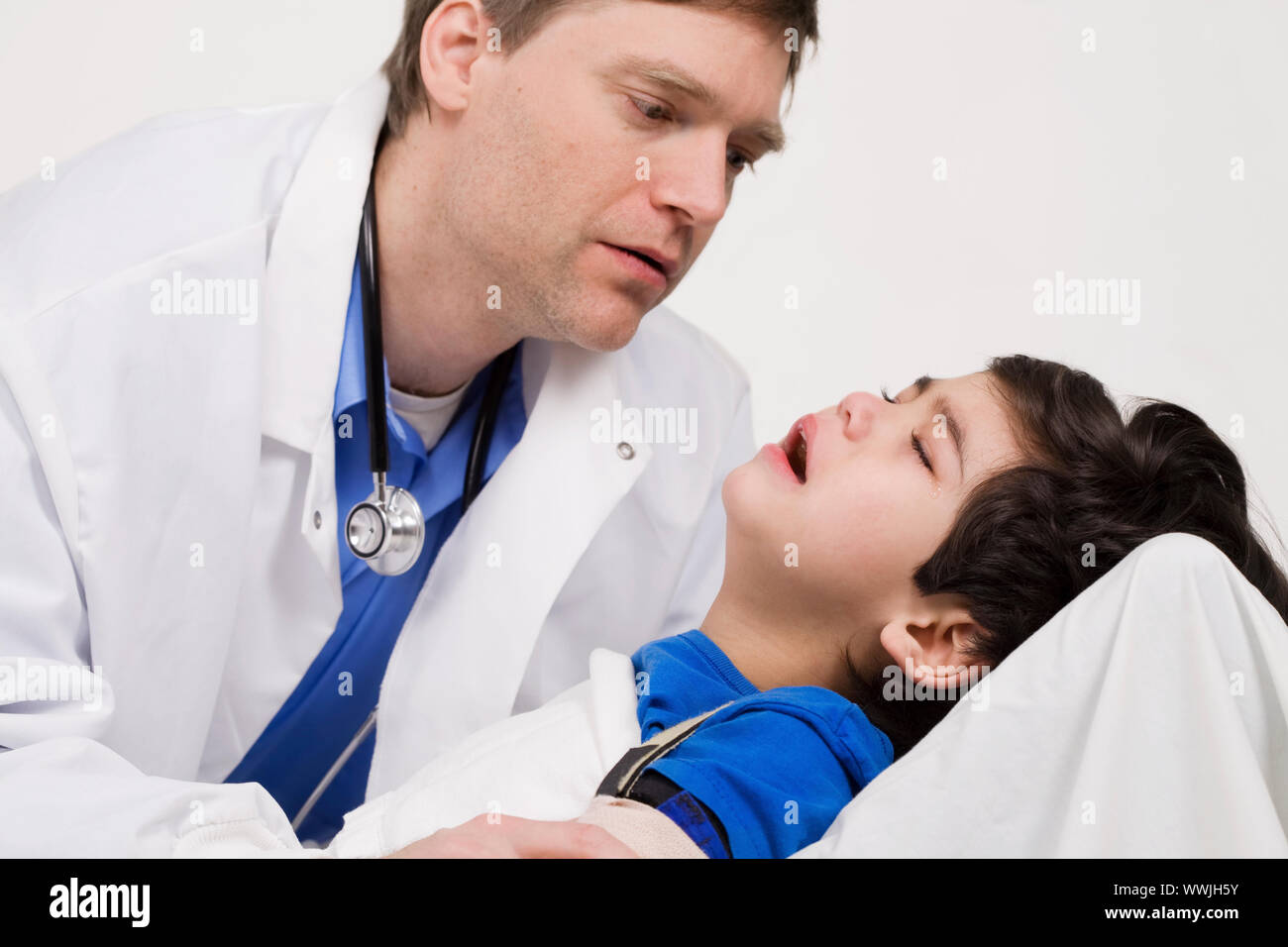 Männlicher Arzt Anfang der vierziger Jahre beruhigende fünf Jahre alte behinderte Patienten während Büro besuchen Stockfoto
