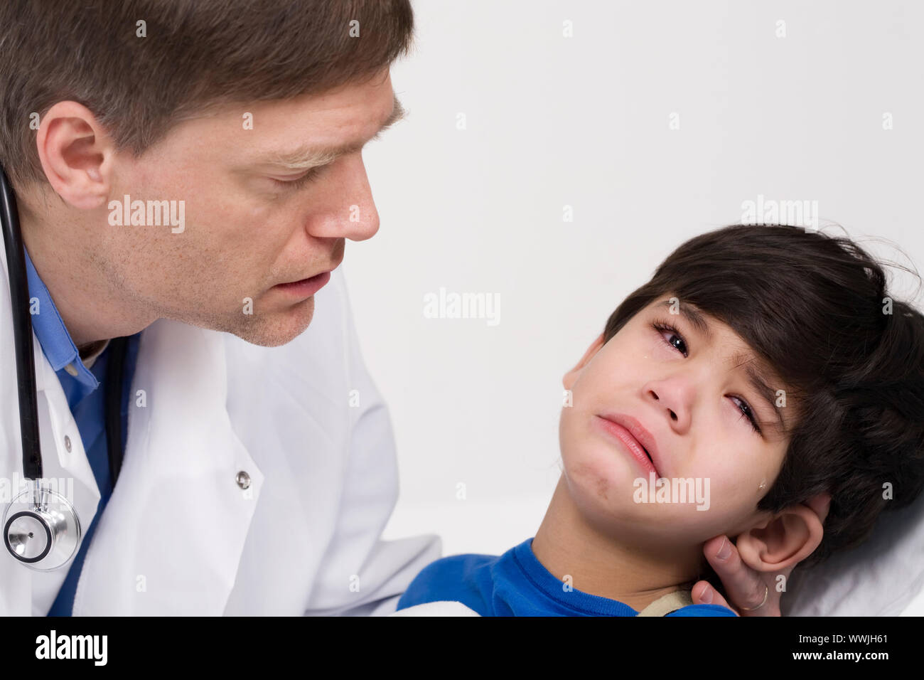 Männlicher Arzt Anfang der vierziger Jahre beruhigende fünf Jahre alte behinderte Patienten während Büro besuchen Stockfoto