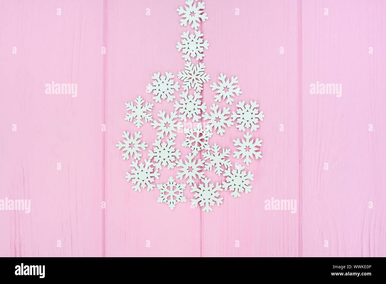 Stilisierte Christmas Ball aus weißem Holz- Schneeflocken auf rosa Hintergrund aus Holz mit Platz für Text. Konzept für Weihnachten Grußkarte, Neues Jahr Stockfoto