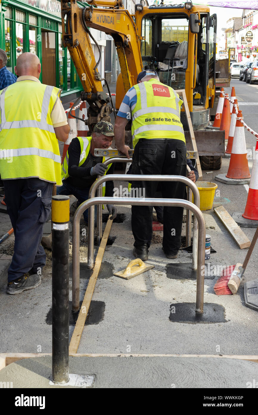 Stadträte, die an der Installation neuer Fahrradgeländer oder Fahrradparkplätze in der High Street in Killarney, County Kerry, Irland, arbeiten Stockfoto