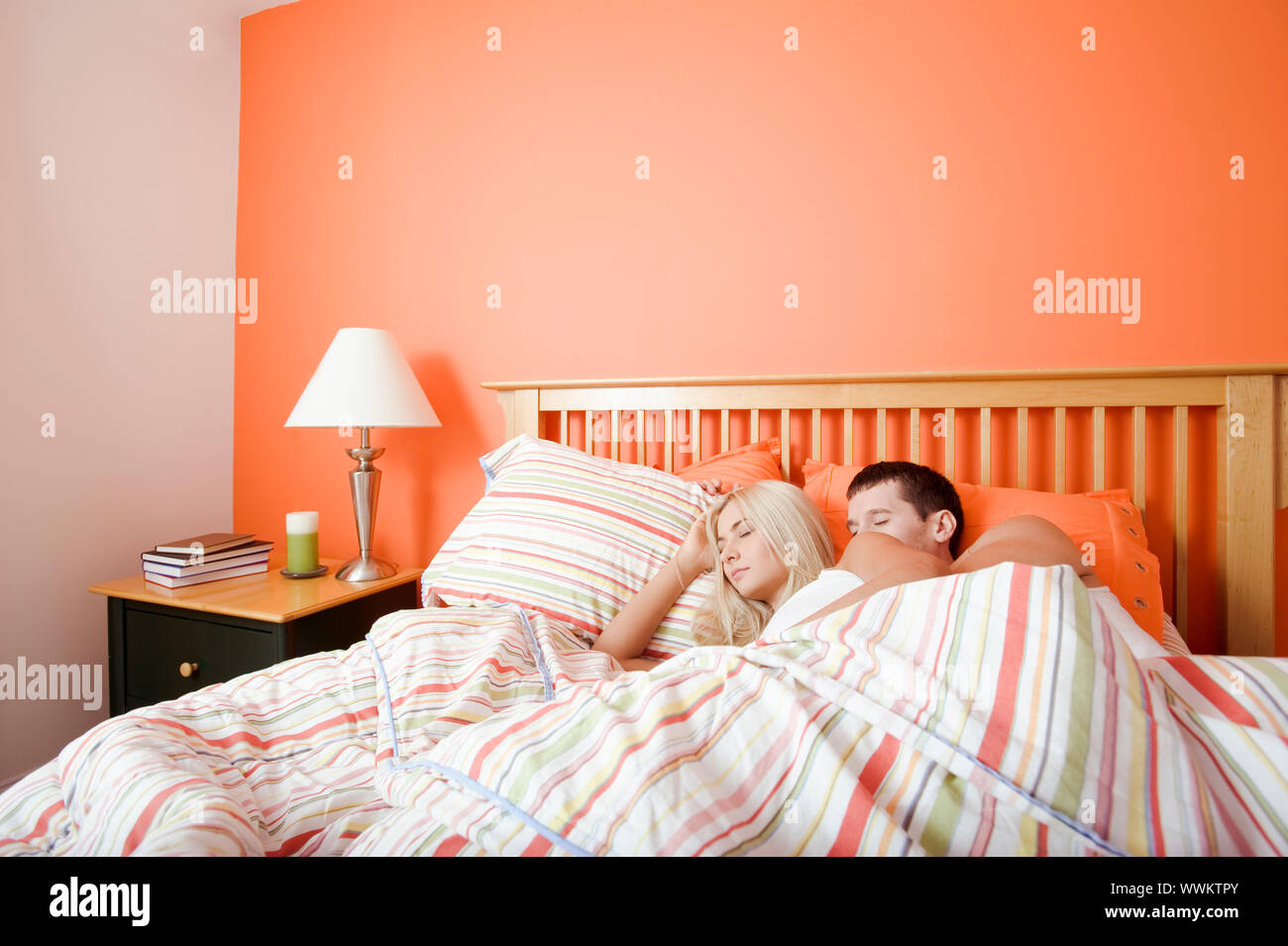 Junges Paar Schlaf eng zusammen unter einer gestreiften Bettdecke. Horizontalen Schuss. Stockfoto