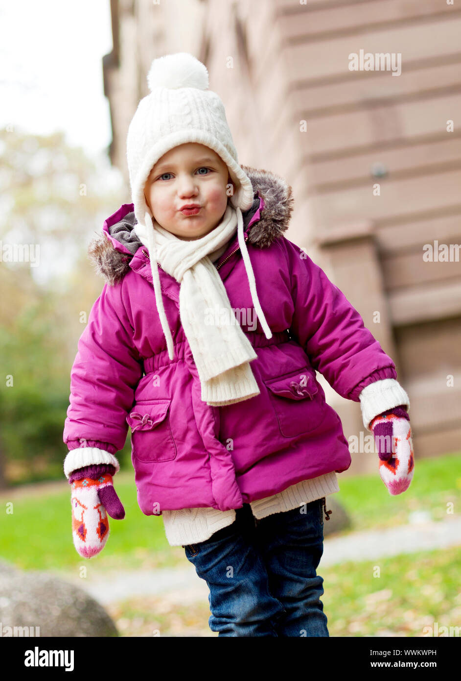 Junge Mädchen in einem rosa Mantel mit Pelzkragen spielen im Herbst Stockfoto