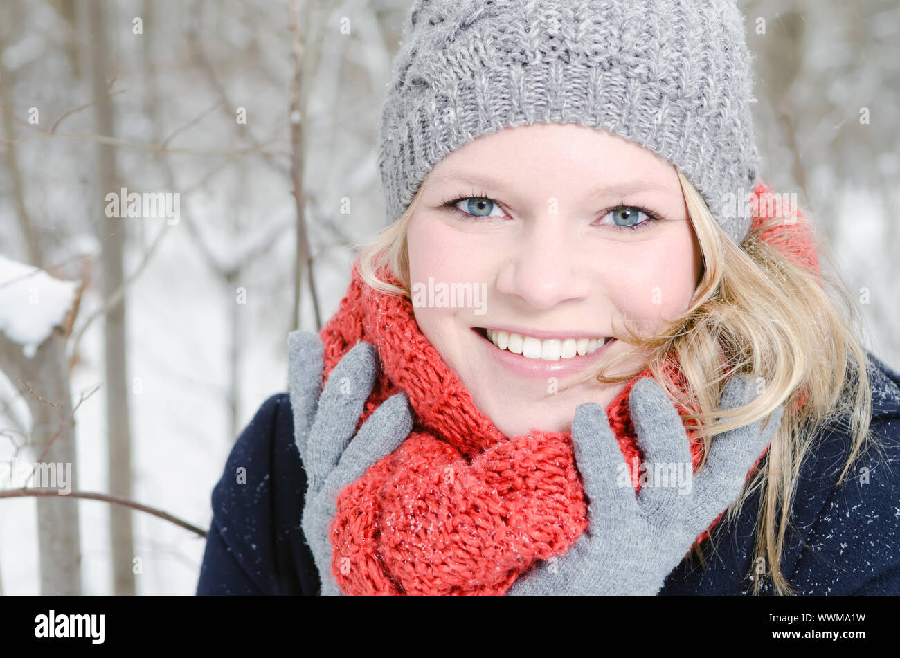 Junge blonde Frau mit Mütze und Schal Winterwald Portrait Stockfoto