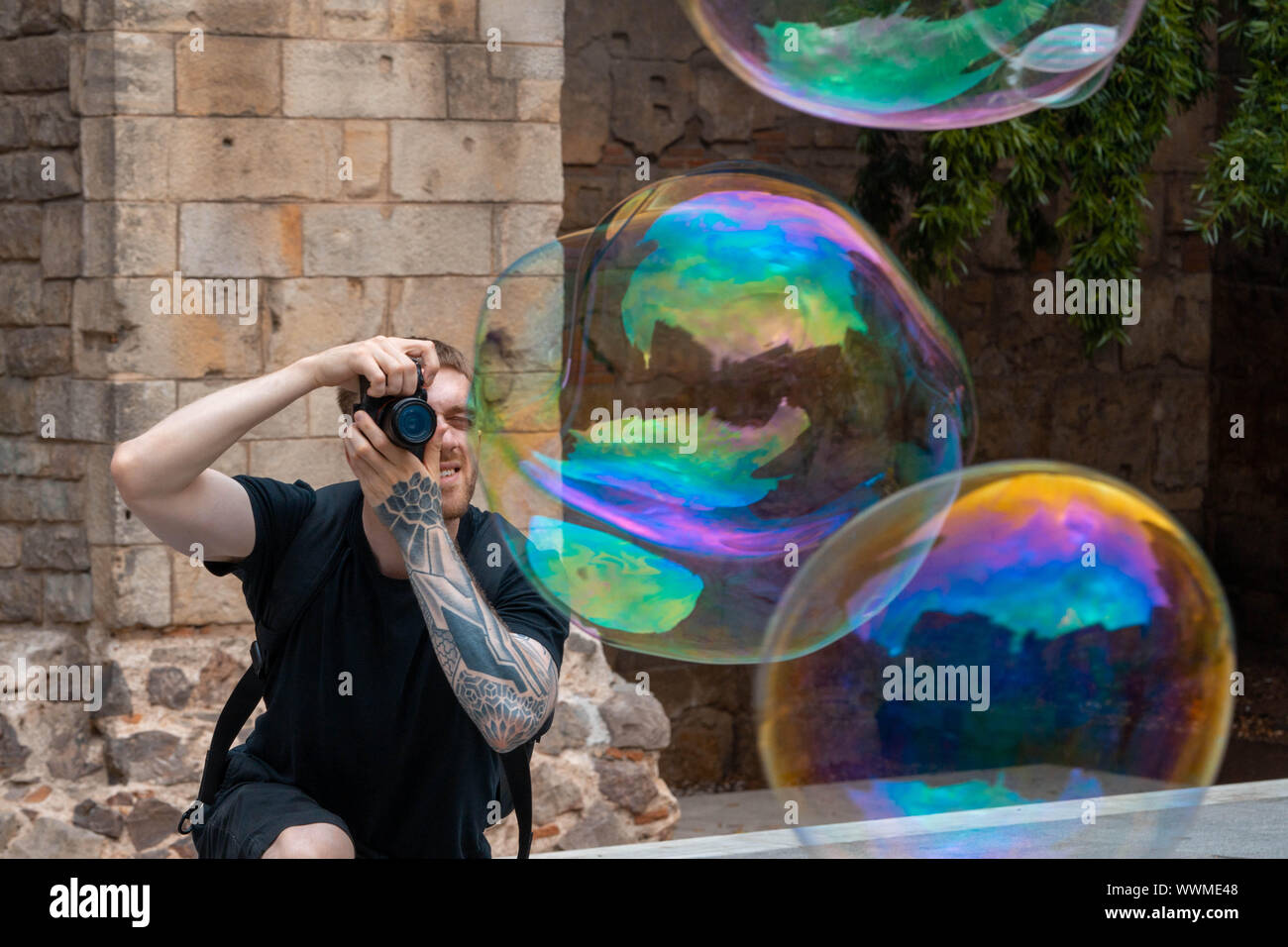 Attraktive lächelnden Mann, Fotos von seifenblasen an der alten, spanischen Stadt. Travel Blogger. Europäische Urlaub voller Lachen und Glück. Stockfoto