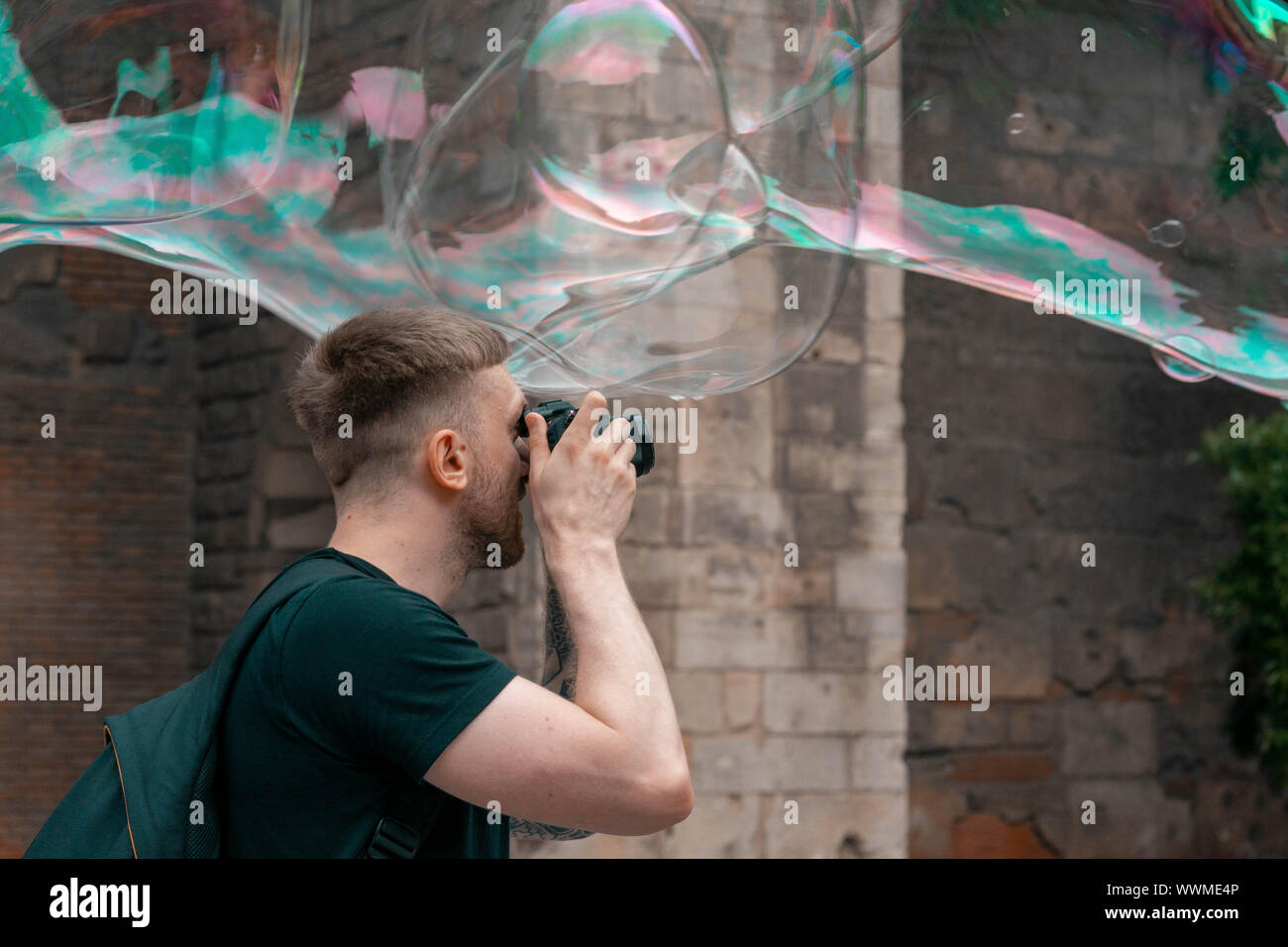 Attraktive lächelnden Mann, Fotos von seifenblasen an der alten, spanischen Stadt. Travel Blogger. Europäische Urlaub voller Lachen und Glück. Stockfoto