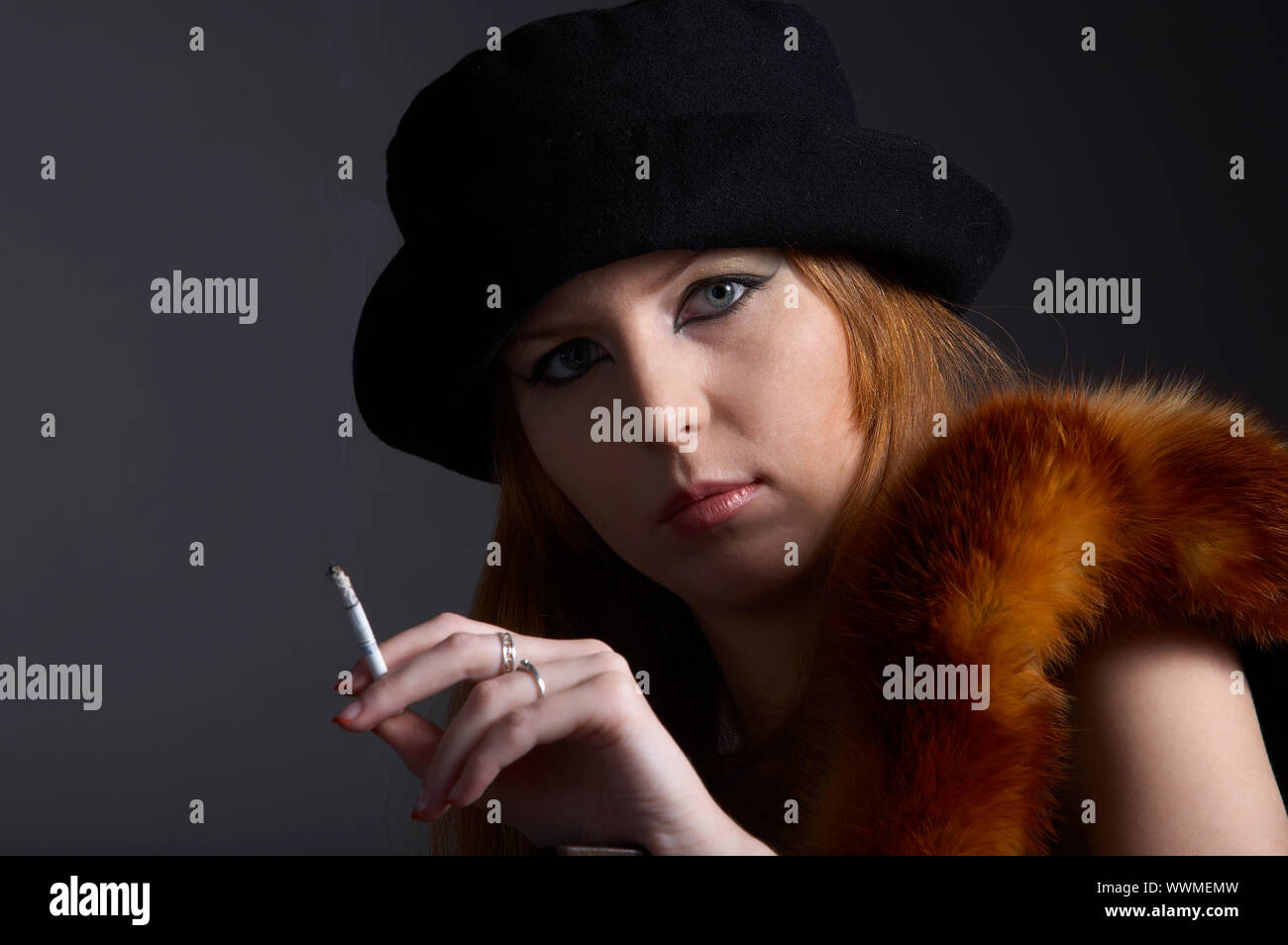 Portrait von schöne rothaarige blasse Haut Model in Pelz Fuchs Schal und schwarzen Hut mit Zigarette Stockfoto