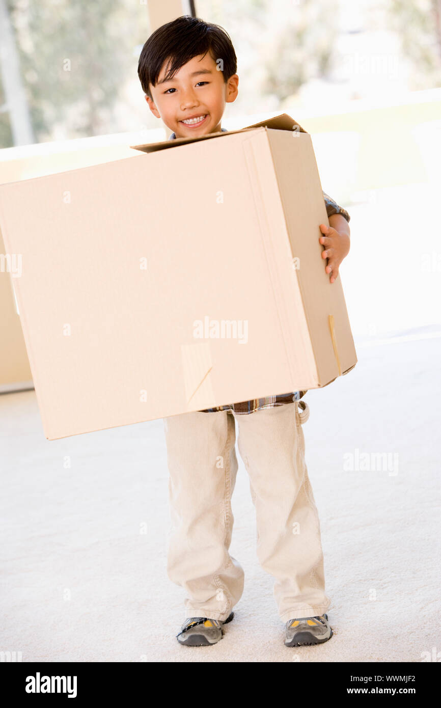 Junge mit Box im neuen Hause lächelnd Stockfoto