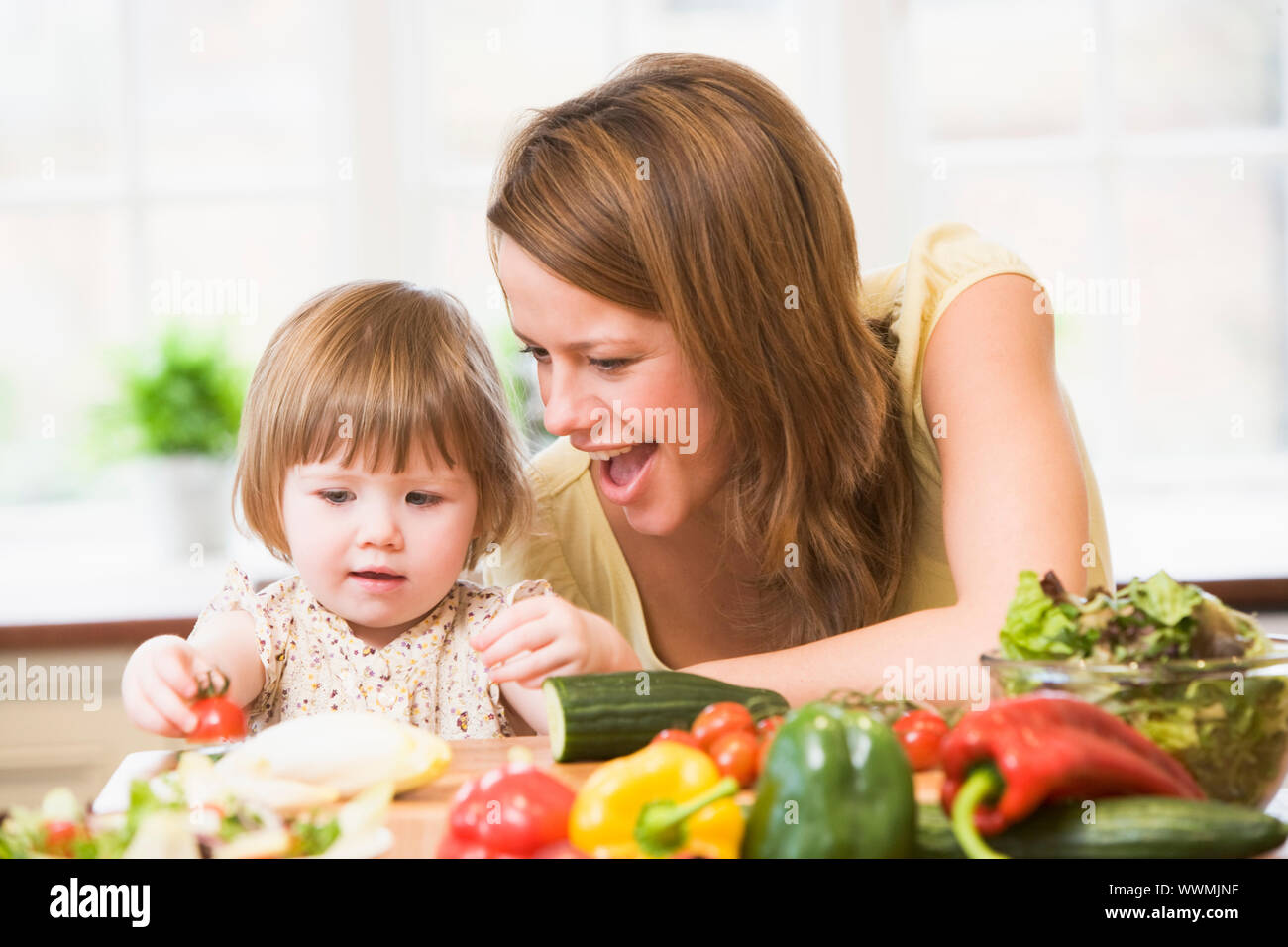 Mutter und Tochter in der Küche machen einen Salat lächelnd Stockfoto