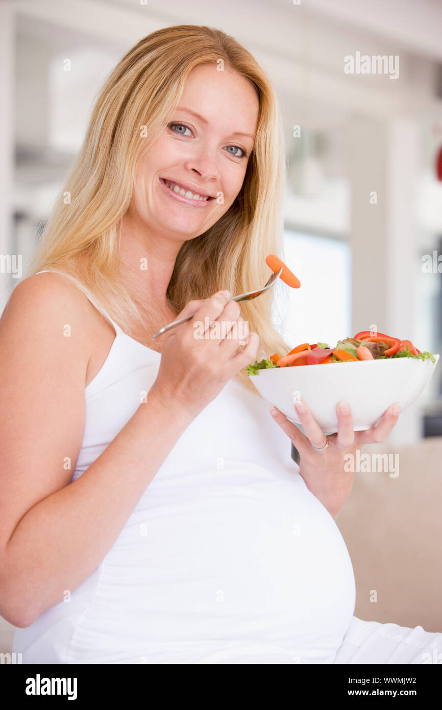Schwangere Frau mit Schüssel Salat lächelnd Stockfoto