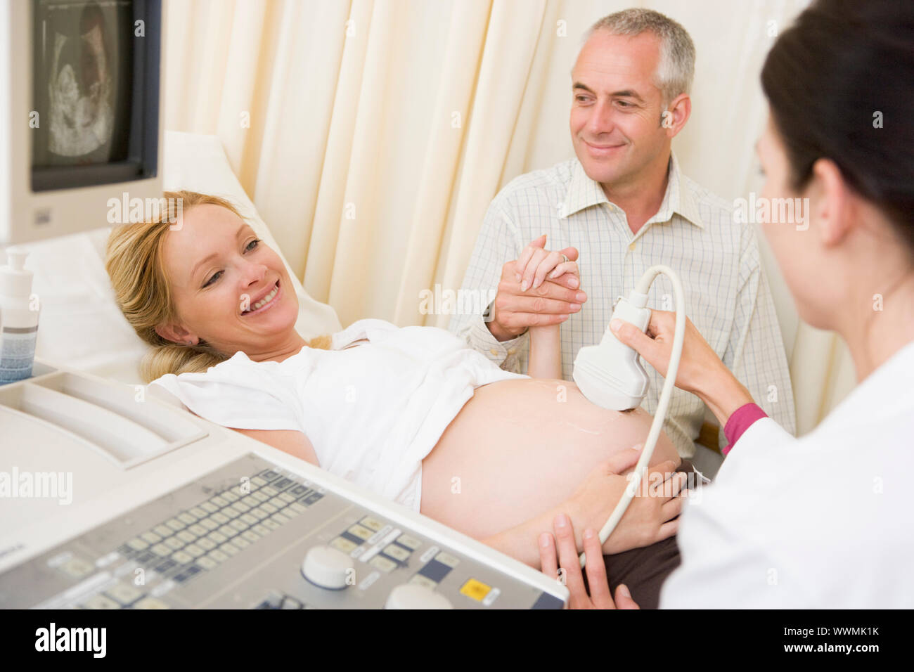 Schwangere Frau Ultraschall von Arzt mit Ehemann Watch Stockfoto