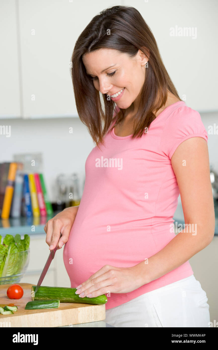 Schwangere Frau in der Küche machen einen Salat und lächelnd Stockfoto