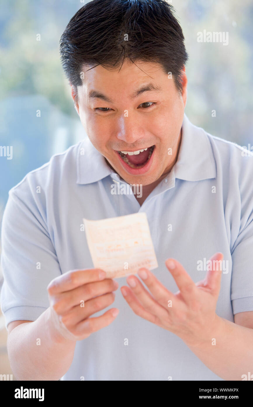 Mann mit Lotto-Ticket aufgeregt und lächelnd Stockfoto