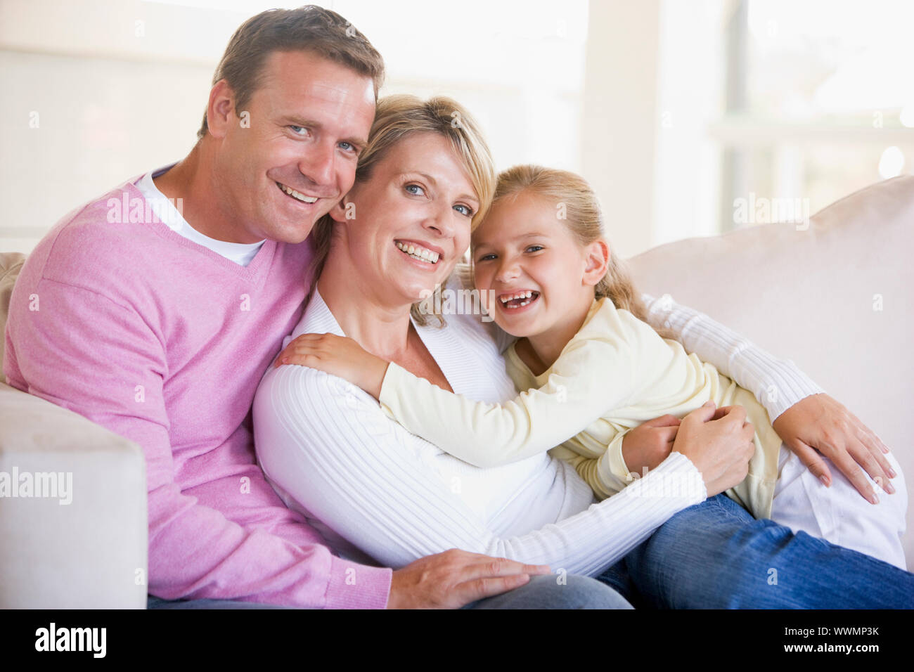 Familie sitzt im Wohnzimmer lächelnd Stockfoto