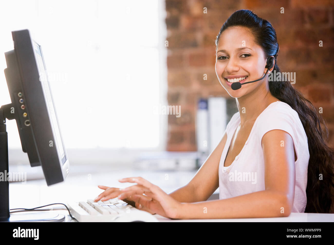 Im Büro Geschäftsfrau das Headset auf, und geben Sie auf dem Computer s Stockfoto