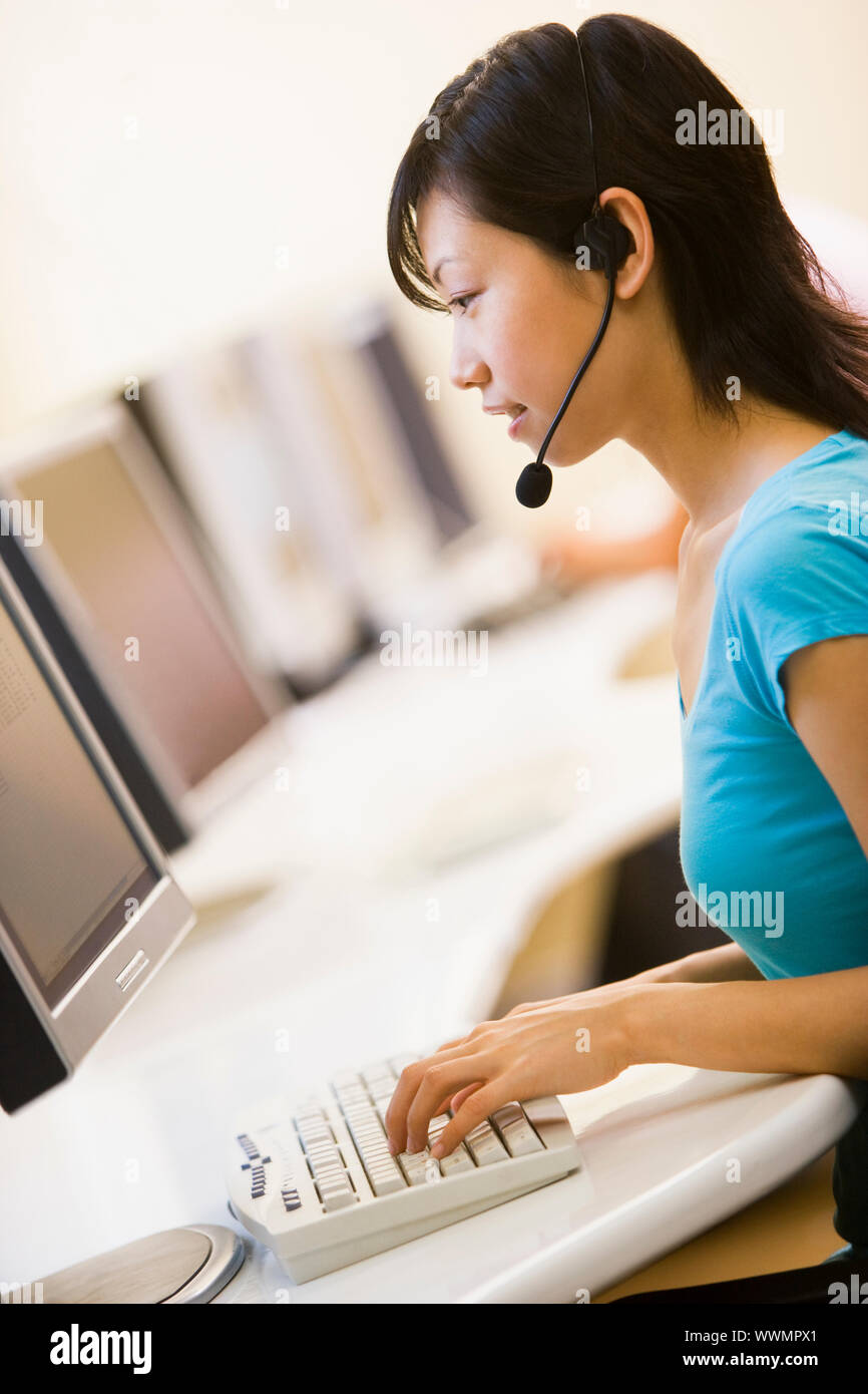 Frau trägt Kopfhörer sitzen in Computer Zimmer eingeben Stockfoto