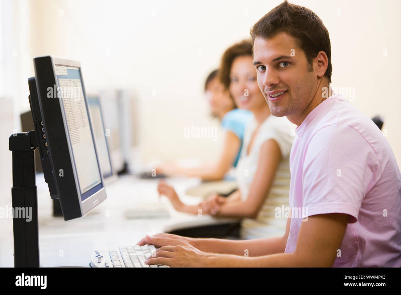 Drei Leute sitzen im Computerraum Typisierung und lächelnd Stockfoto