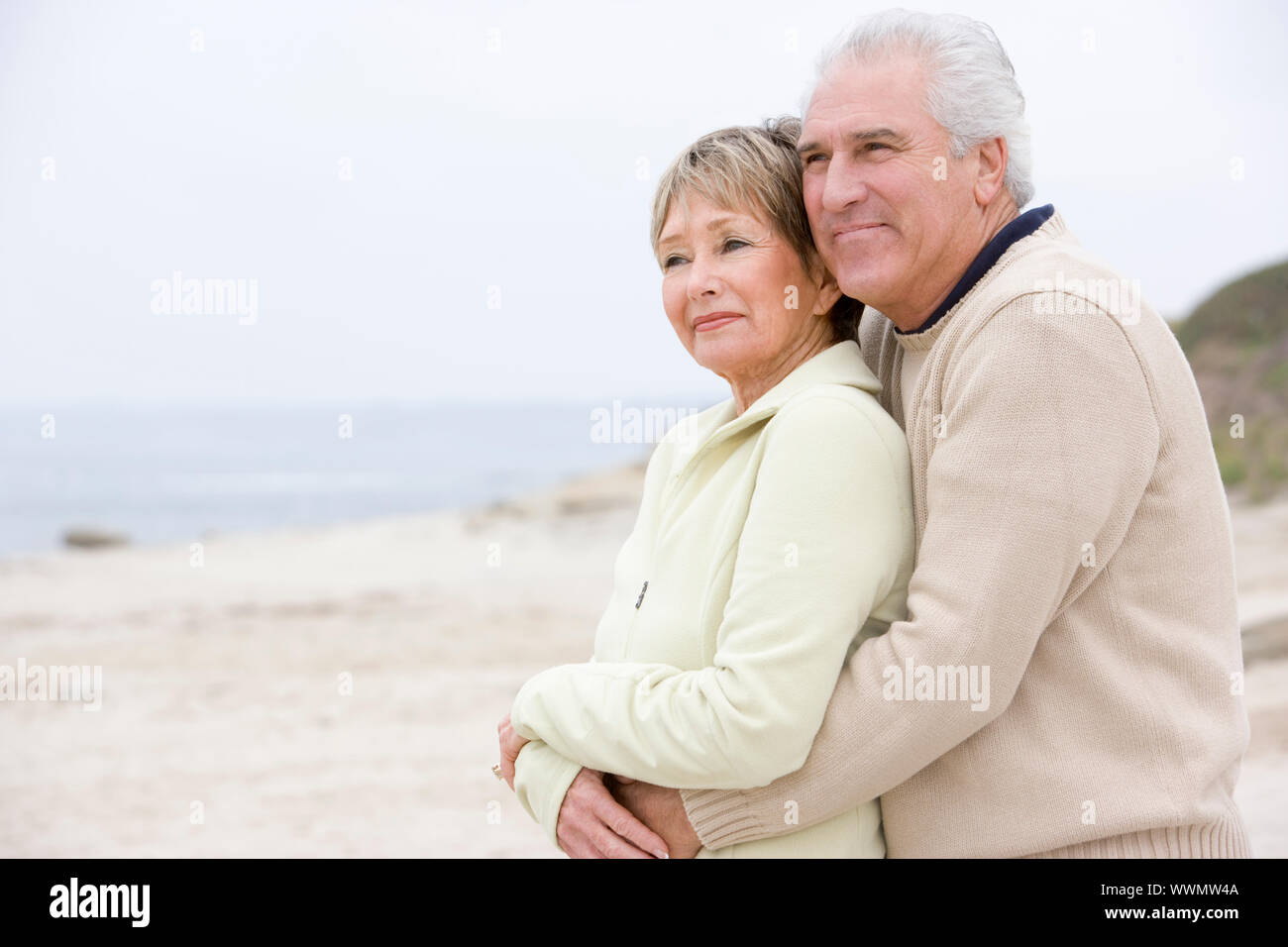 Paar am Strand umarmen und lächelnd Stockfoto