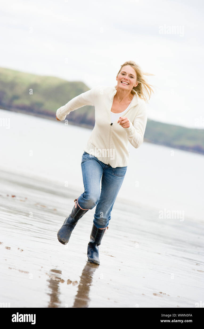 Frau am Strand lächelnd läuft Stockfoto