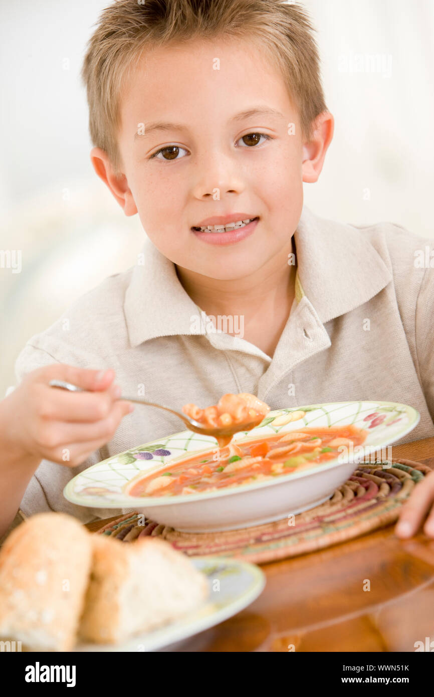 Kleiner Junge drinnen essen Suppe Stockfoto
