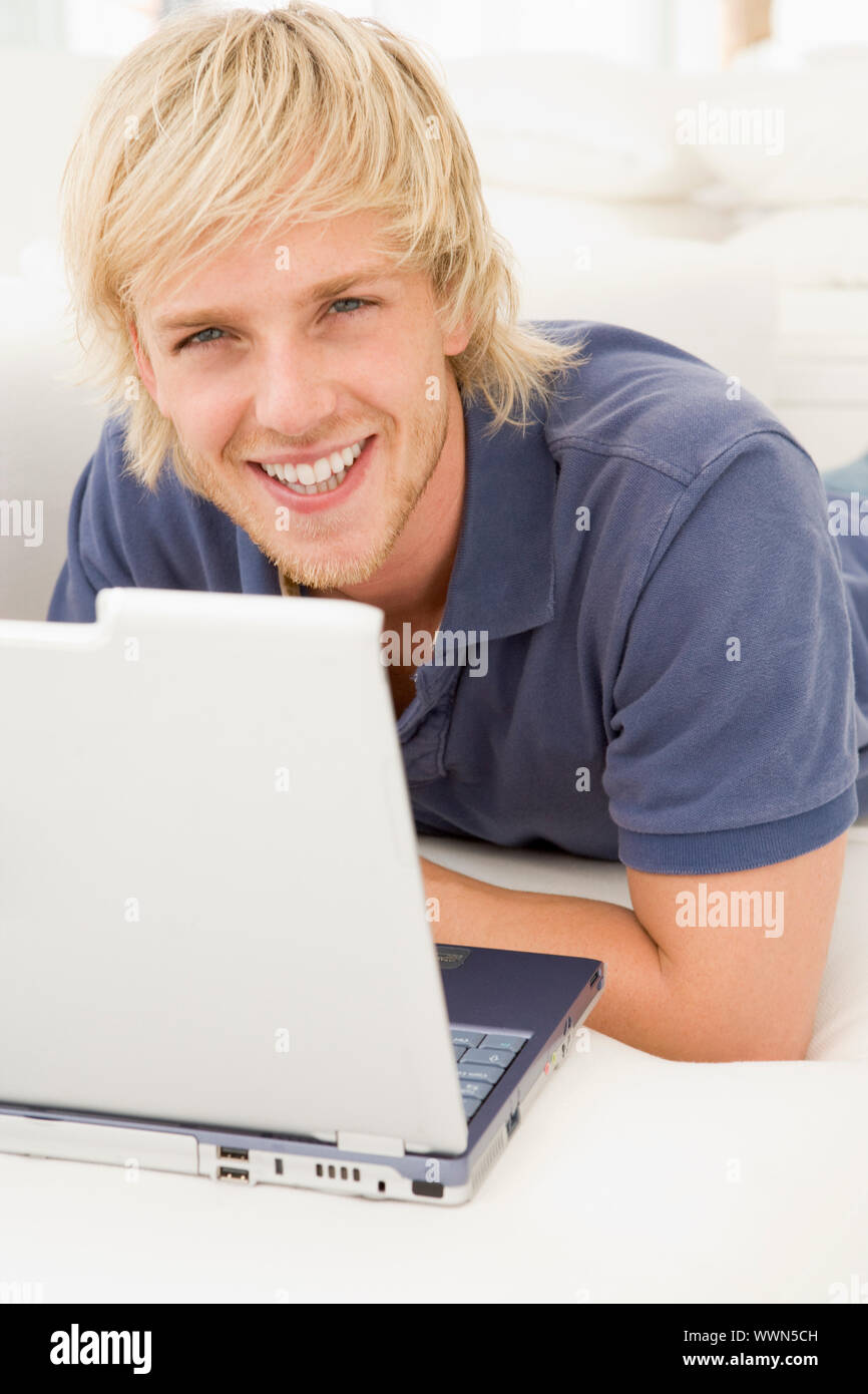 Mann im Wohnzimmer mit Laptop lächelnd Stockfoto