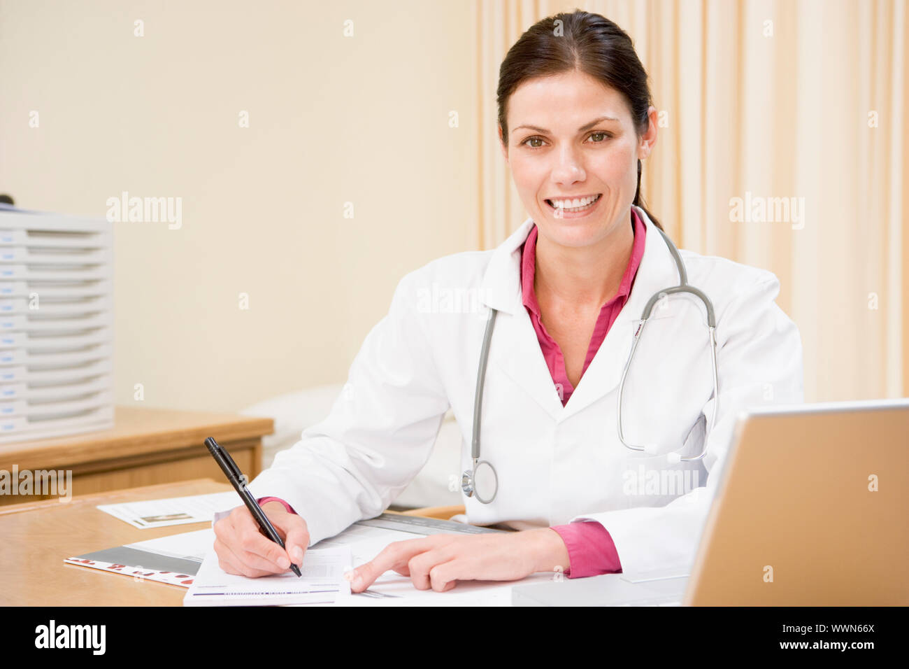 Arzt mit Laptop schreiben in Arztpraxis lächelnd Stockfoto