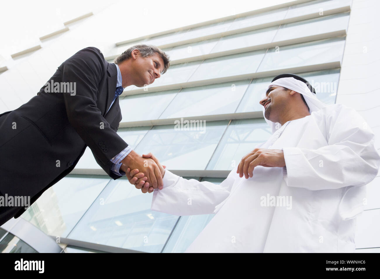 Zwei Geschäftsleute im Freien durch Gebäude Händeschütteln und lächelnd Stockfoto