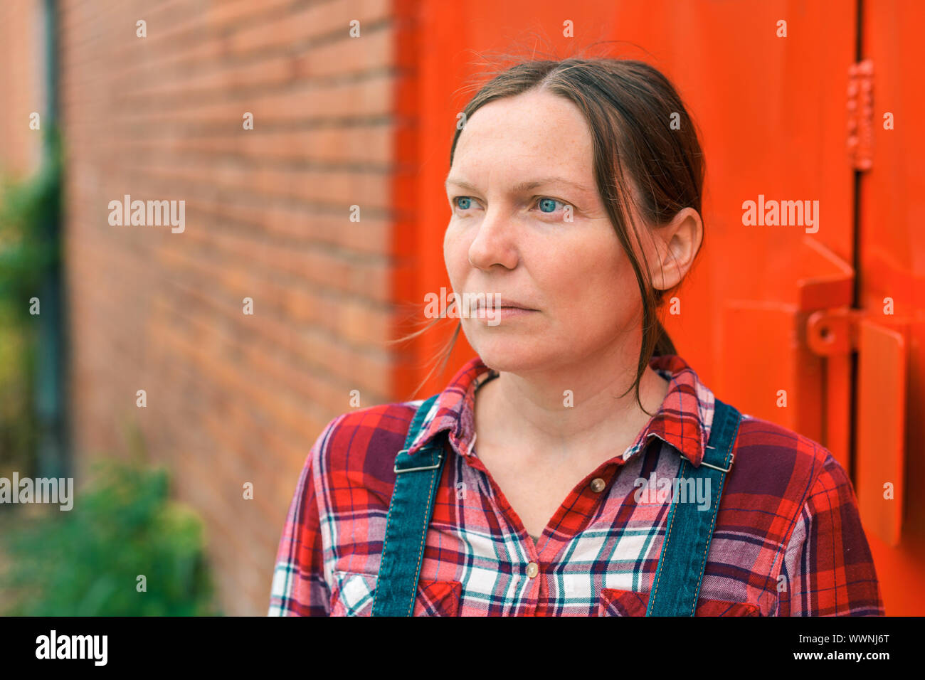 Portrait von zuversichtlich weiblich Landwirt vor dem Bauernhaus im Abstand suchen, Denken und Planen Stockfoto
