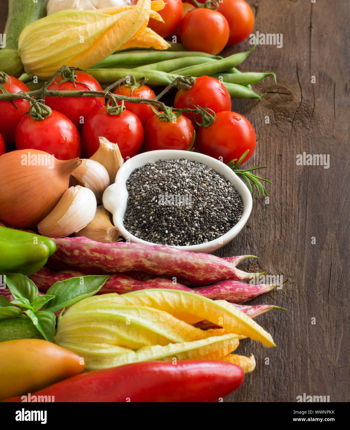 Raw Chia Samen in der Schüssel und Gemüse auf einem Holztisch Stockfoto