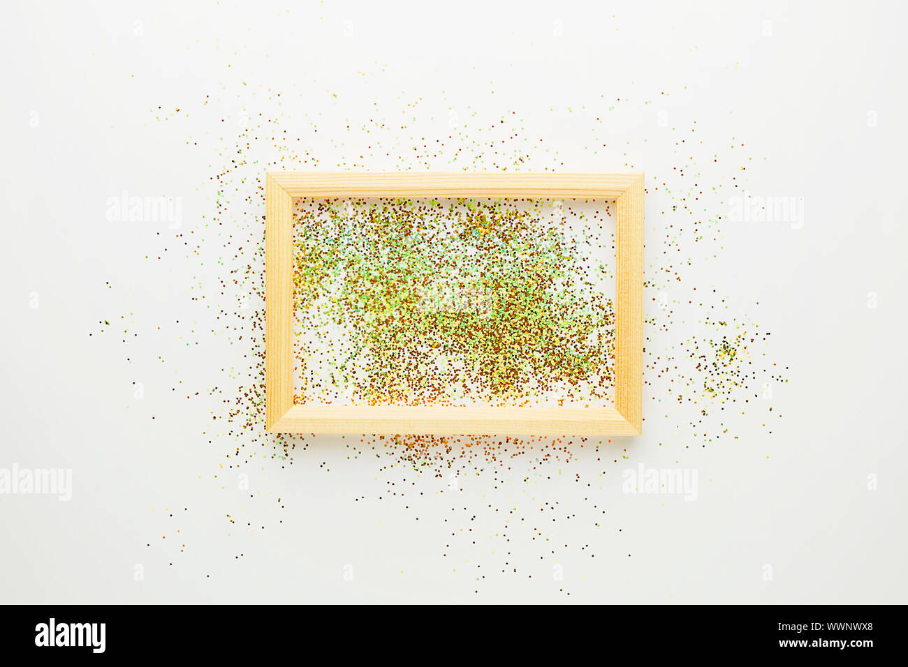 Kreative Gestaltung von farbigen funkelt Konfetti und Holzrahmen auf weißem Hintergrund, oben flach zu legen. Urlaub minimalistisches Design Konzept Stockfoto