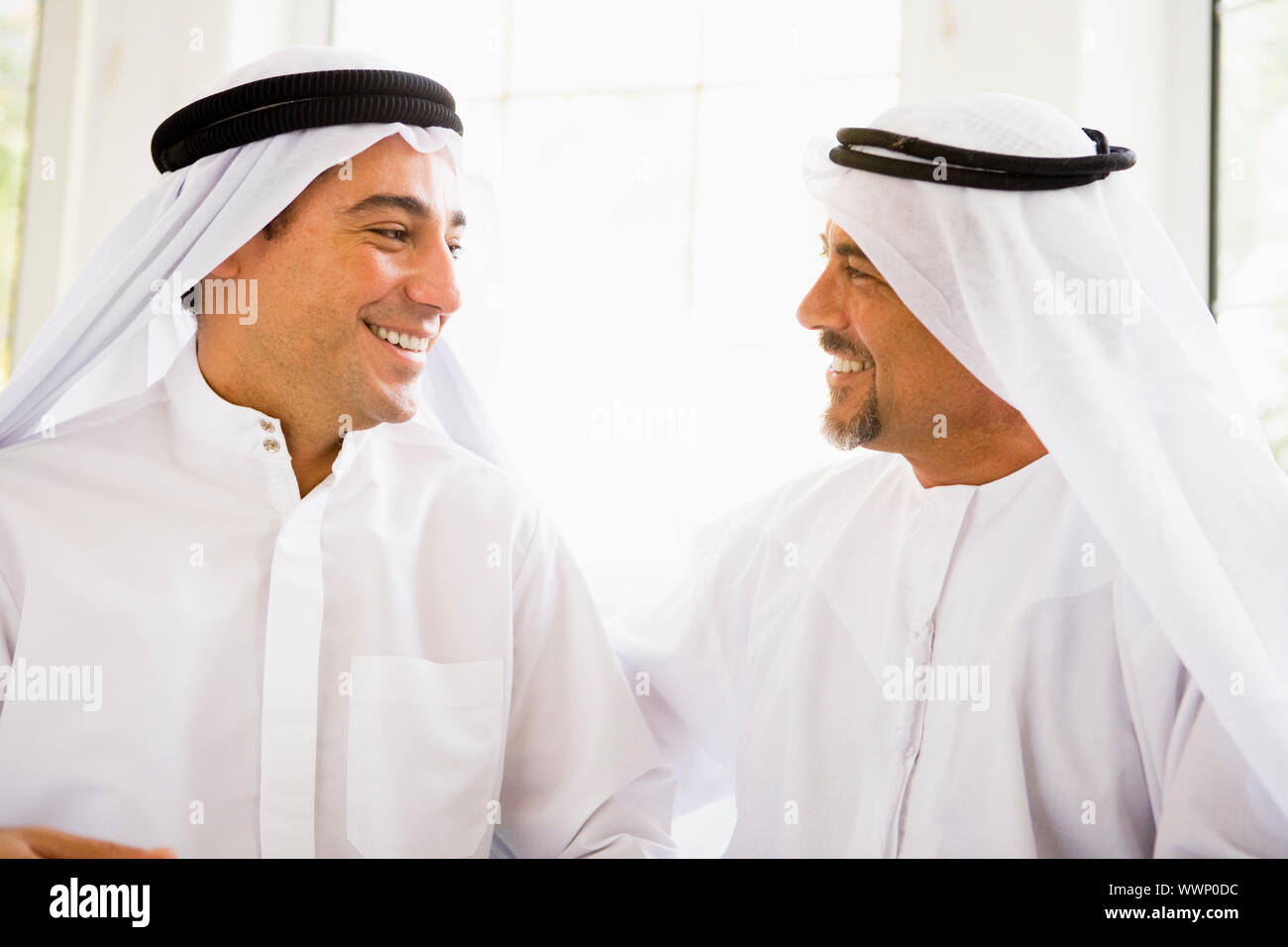 Zwei Männer sitzen im Haus sprechen und Lächeln auf den Lippen (high-Key) Stockfoto