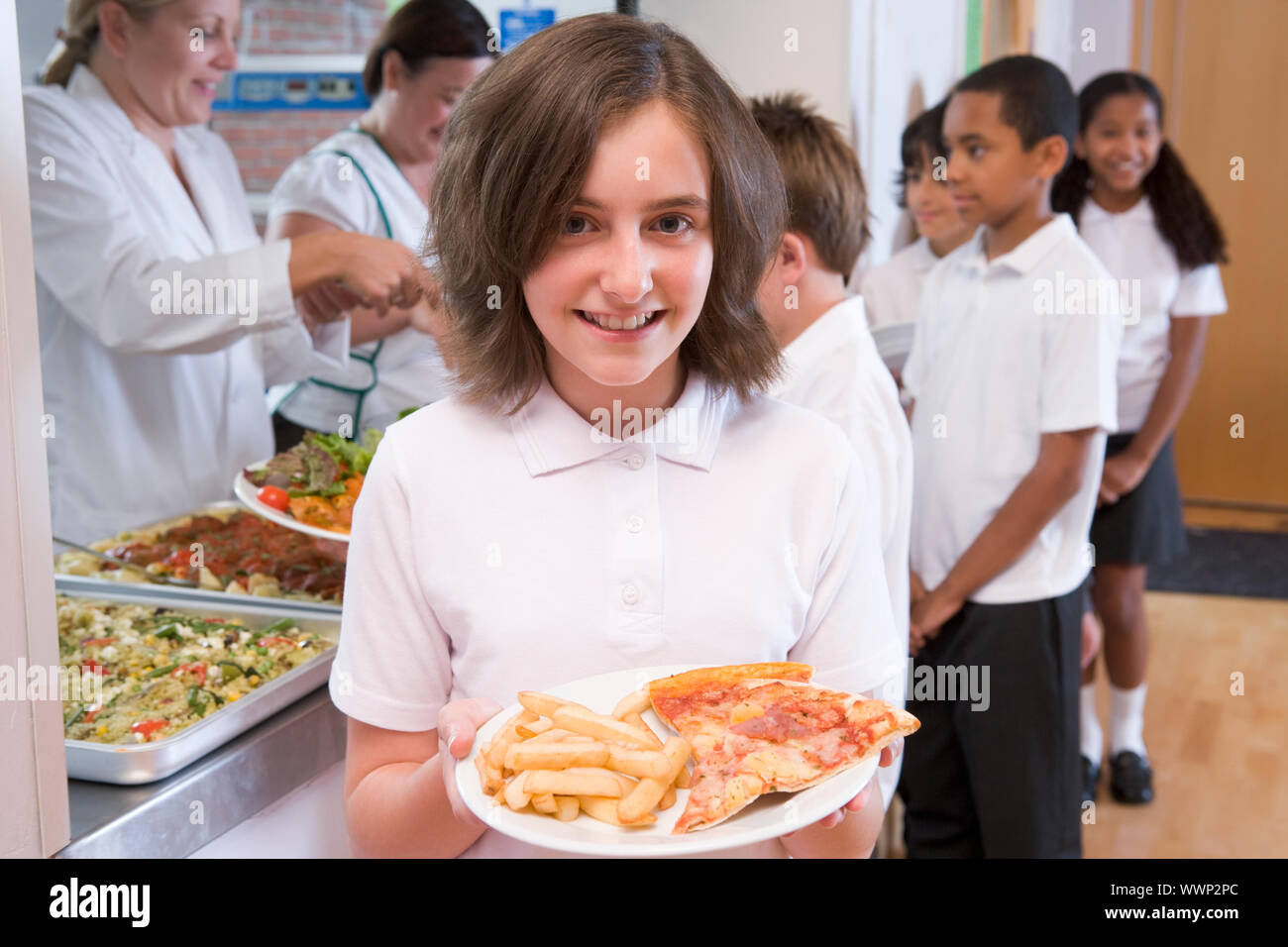 Schüler in der Cafeteria Schlange mit einem hält ihre gesunde Mahlzeit und Blick in die Kamera (Schärfentiefe) Stockfoto
