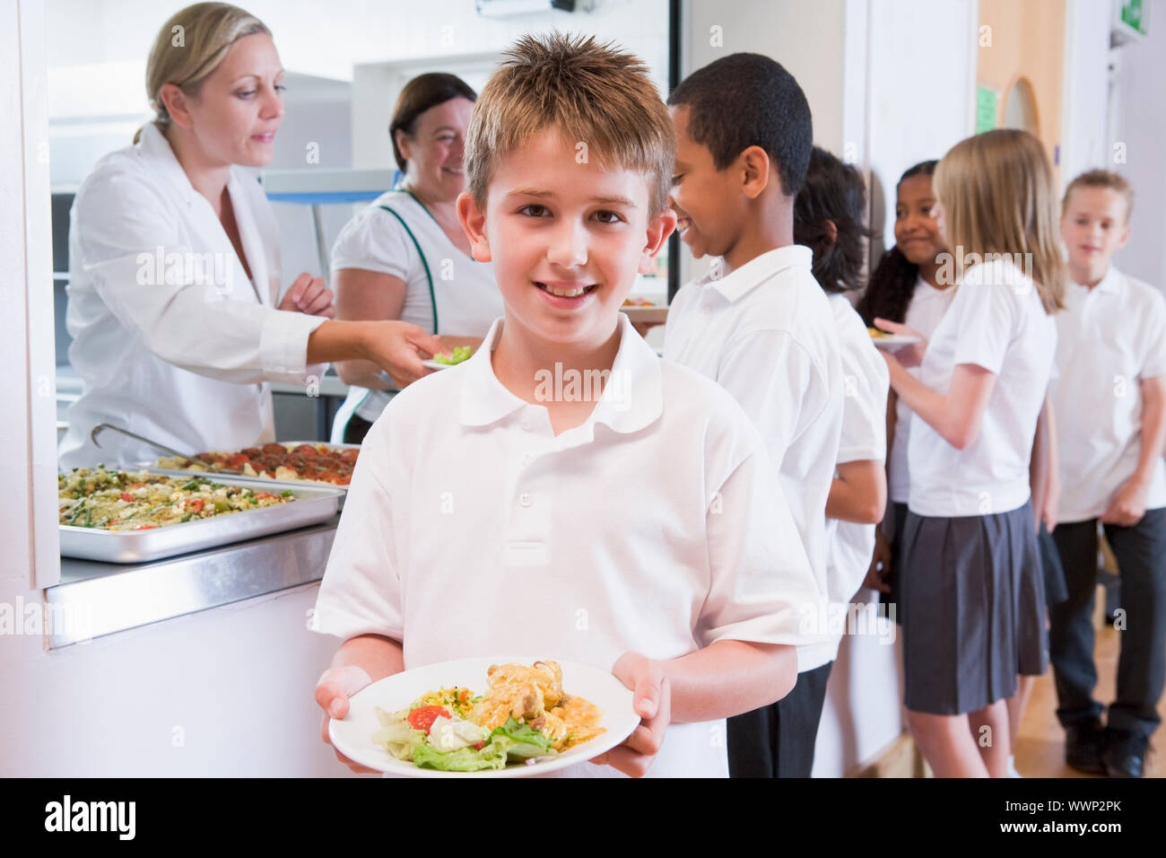 Schüler in der Cafeteria Schlange mit einem hält seine gesunde Mahlzeit und Blick in die Kamera (Schärfentiefe) Stockfoto