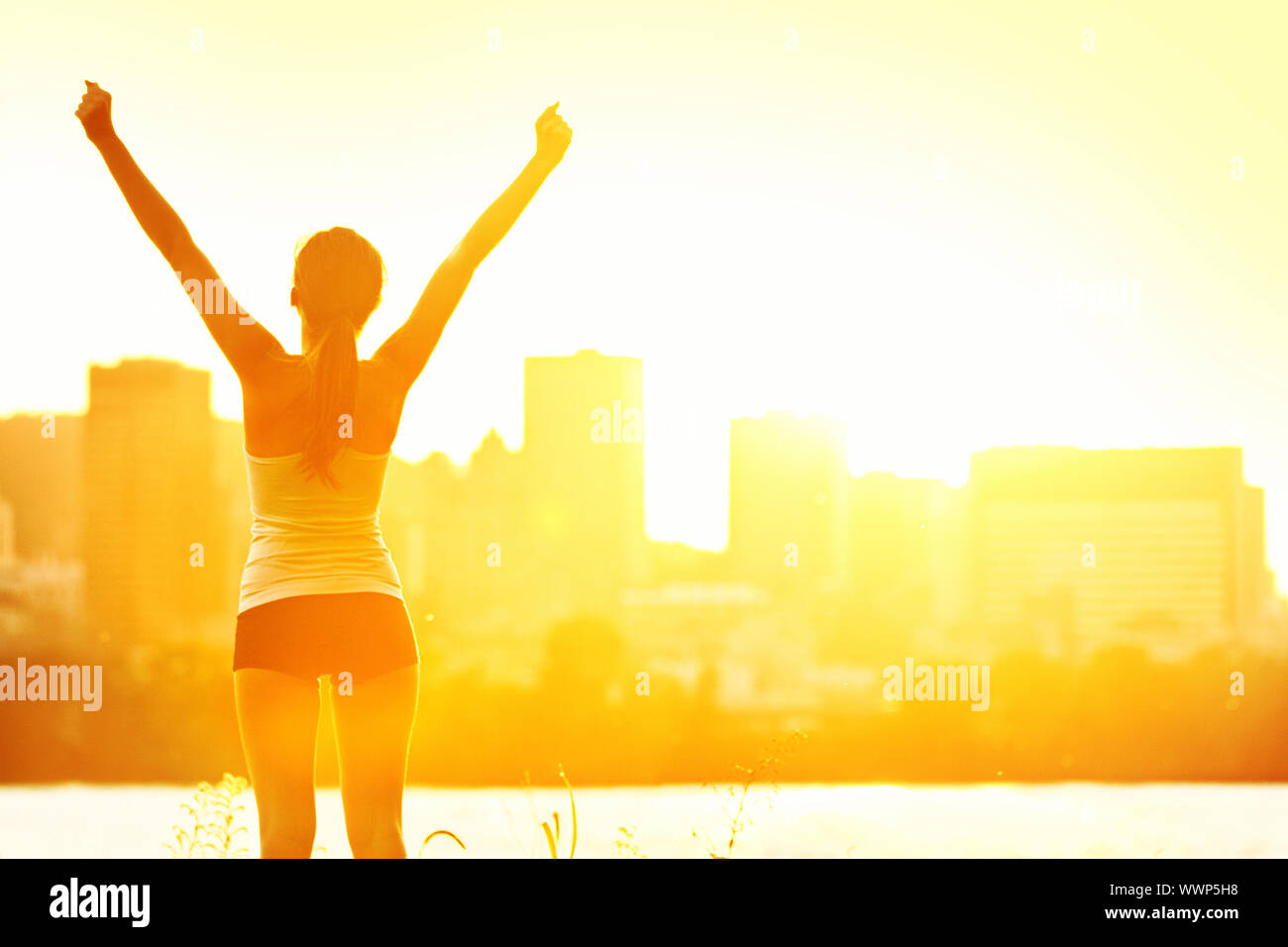 Erfolg Sieger Frau mit Waffen stand fröhlich nach dem freien Training. Die Hälfte Silhouette am sonnigen warmen Sommertag mit Sicht auf die City Skyline im Hintergrund, Fr Stockfoto