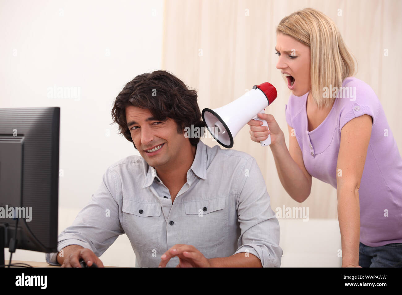 ein Mann tun, Computer und eine Frau auf ihn mit einem Megaphon schreien Stockfoto