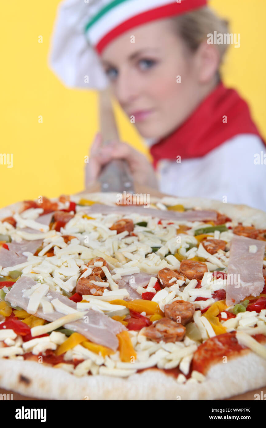weibliche Pizza Koch setzen eine Pizza im Ofen Stockfoto