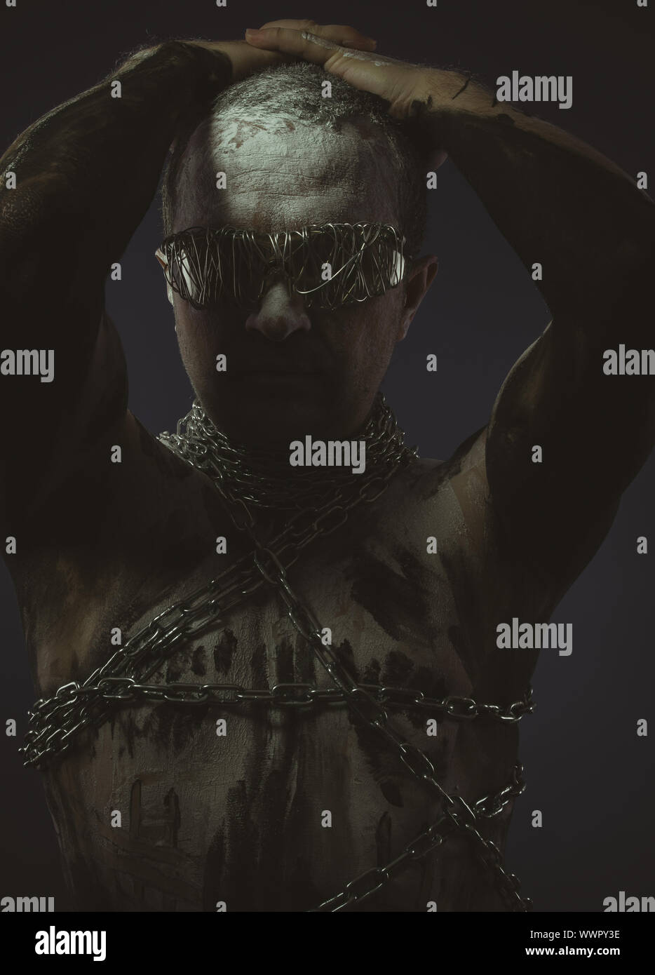 BDSM, Mann mit Ketten durch den Körper und Draht Brille, Haut gemalt schwarz lackiert und weiß Stockfoto