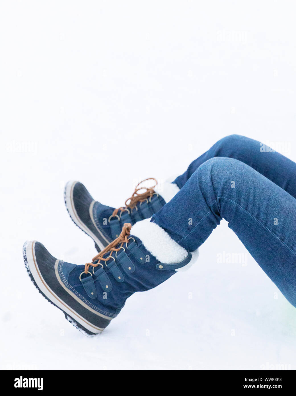 Frau im Schnee mit blauer Schnee Stiefel und Jeans Stockfoto