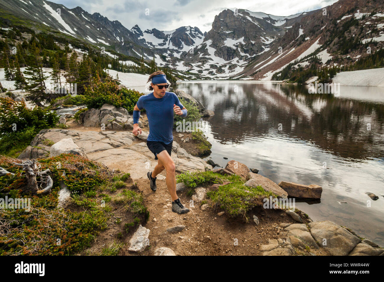 Ein Mann läuft entlang der Ufer des Sees Isabelle in Indian Peaks Wilderness, Colorado. Navajo (L-R), Apache, und Shoshone Peaks sind sichtbar in der backgrou Stockfoto